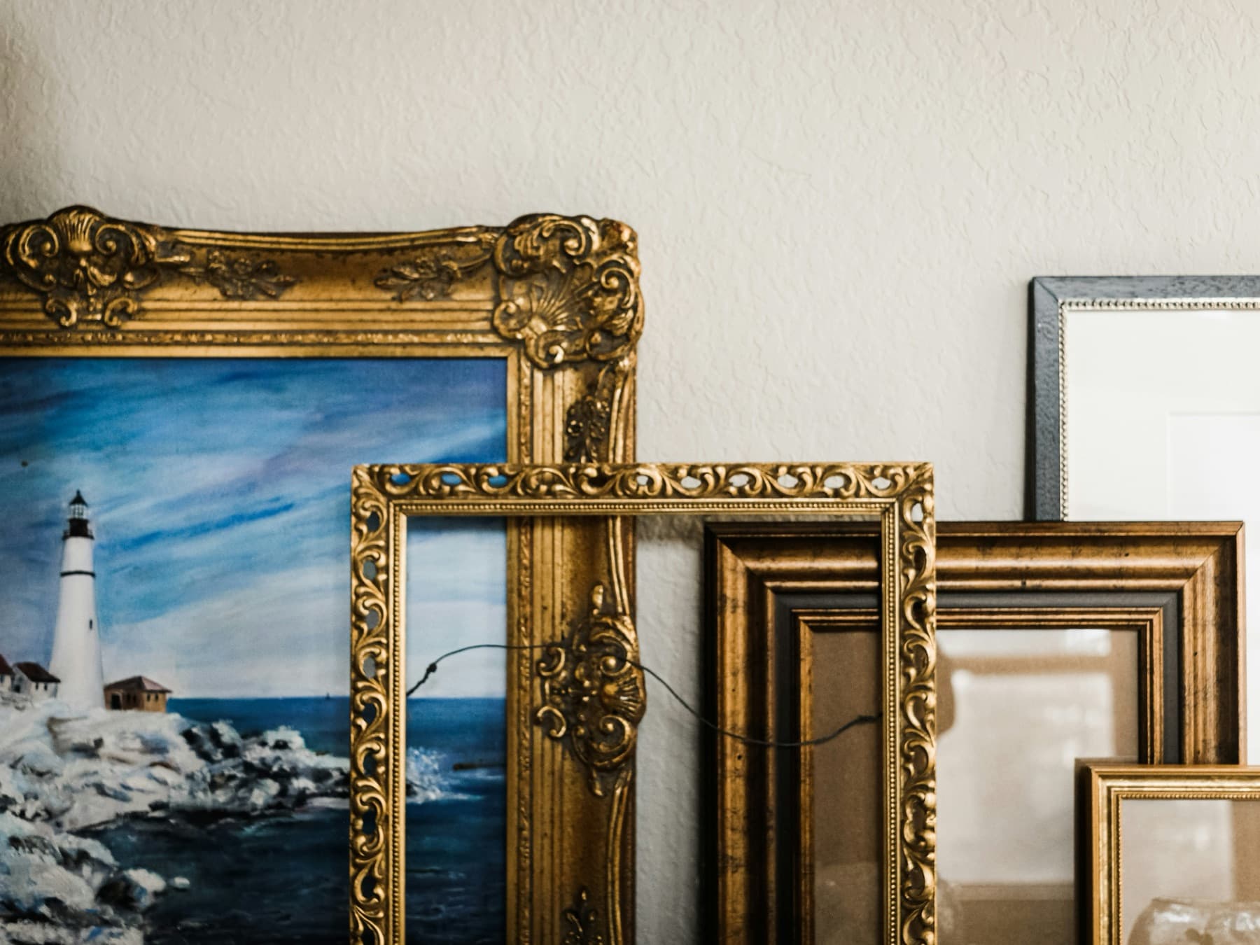 Gilt picture frames leaning against a white wall